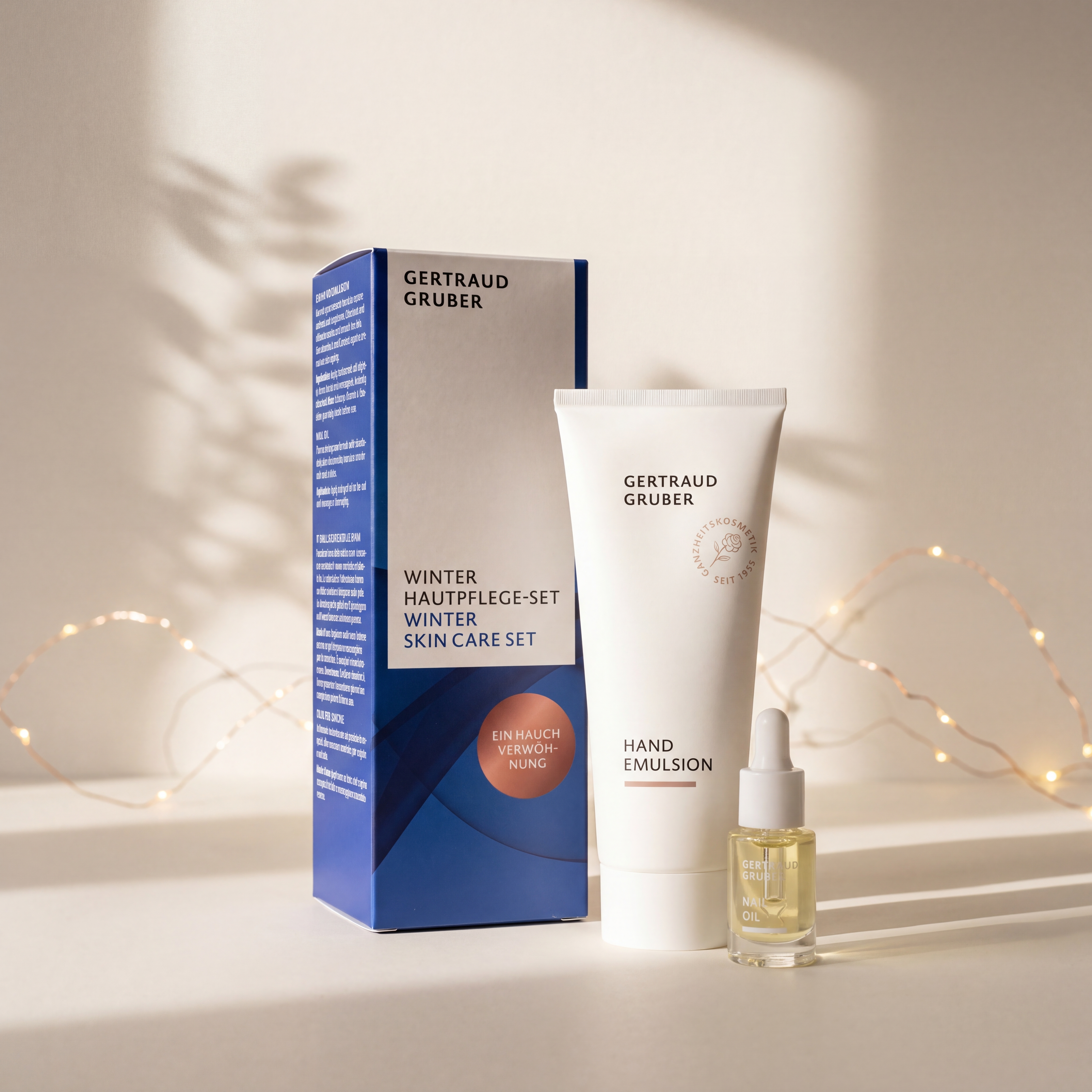 Winter Hautpflege-Set von GERTRAUD GRUBER mit Hand Emulsion und Nail Oil vor der Geschenkverpackung, stimmungsvoll inszeniert mit warmen Lichtern.
