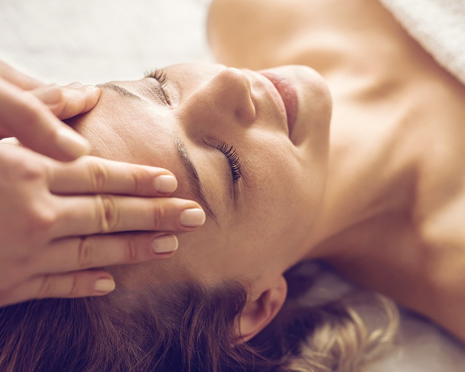 Eine Frau erhält eine entspannende Gesichtsmassage in einem ruhigen Spa-Umfeld.