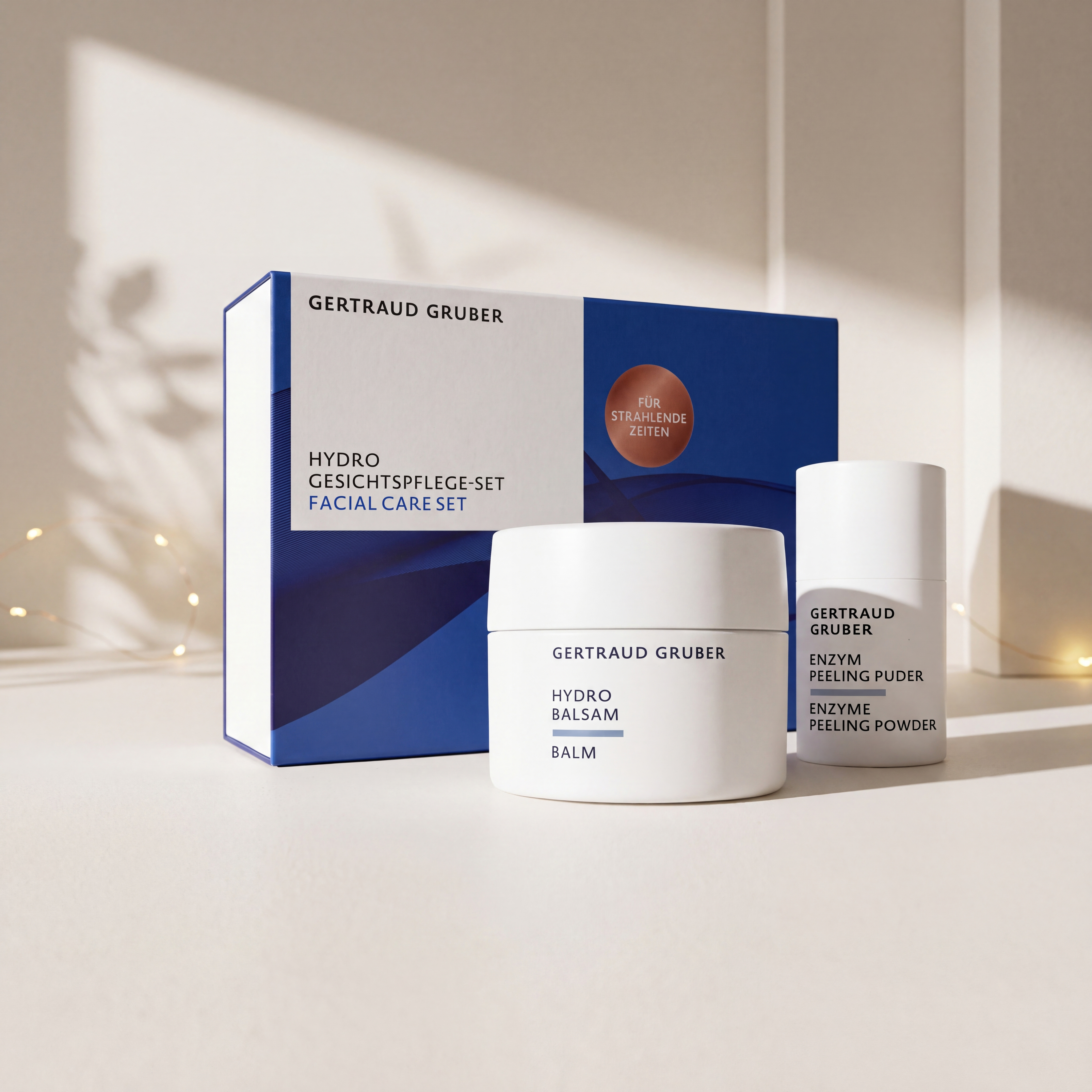 Hydro Gesichtspflege-Set von GERTRAUD GRUBER mit Hydro Balsam und Enzym Peeling Puder vor der Geschenkverpackung, stimmungsvoll inszeniert mit warmen Lichtern