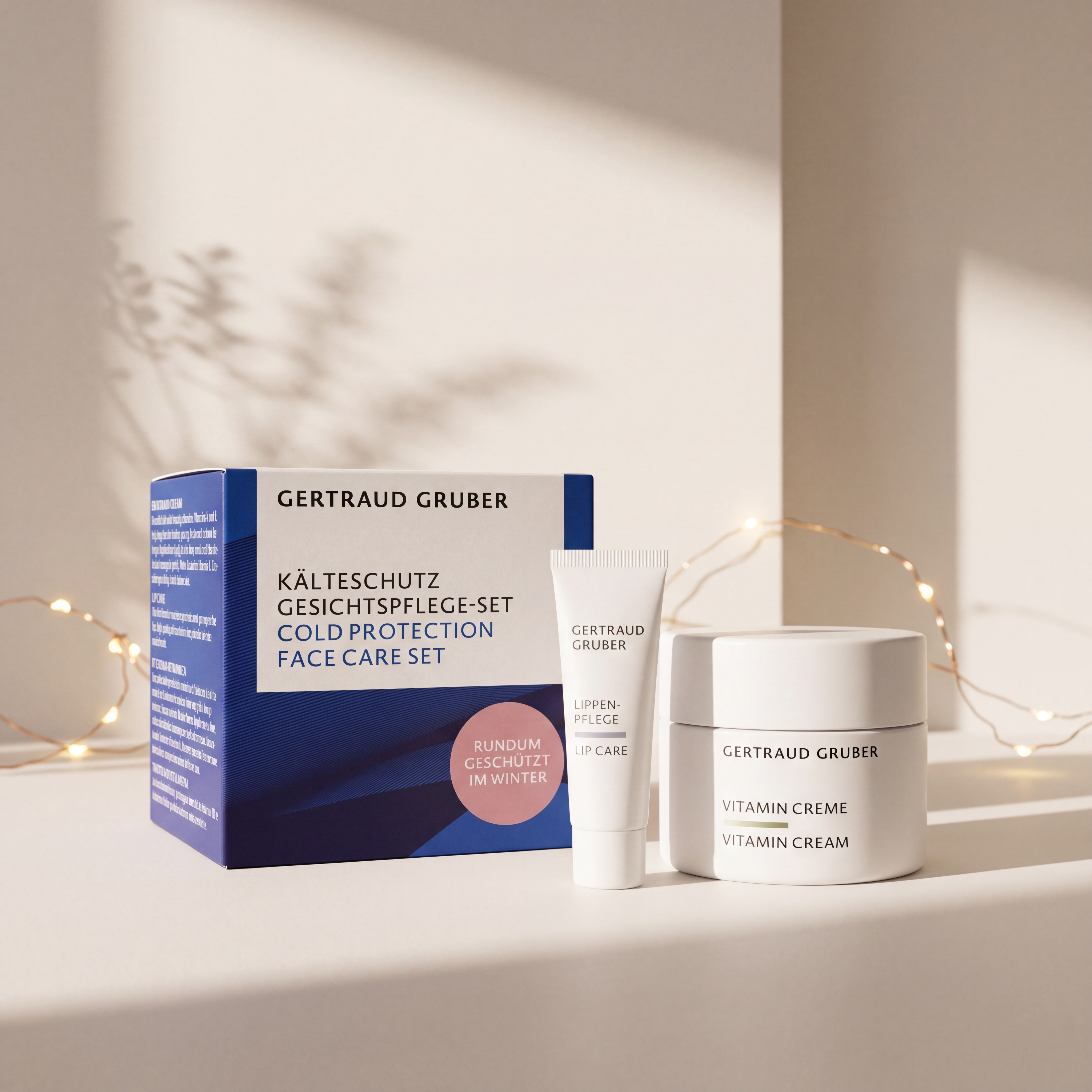Kälteschutz Gesichtspflege-Set von GERTRAUD GRUBER mit Vitamin Creme und Lippenpflege vor der Geschenkverpackung, stimmungsvoll inszeniert mit warmen Lichtern.