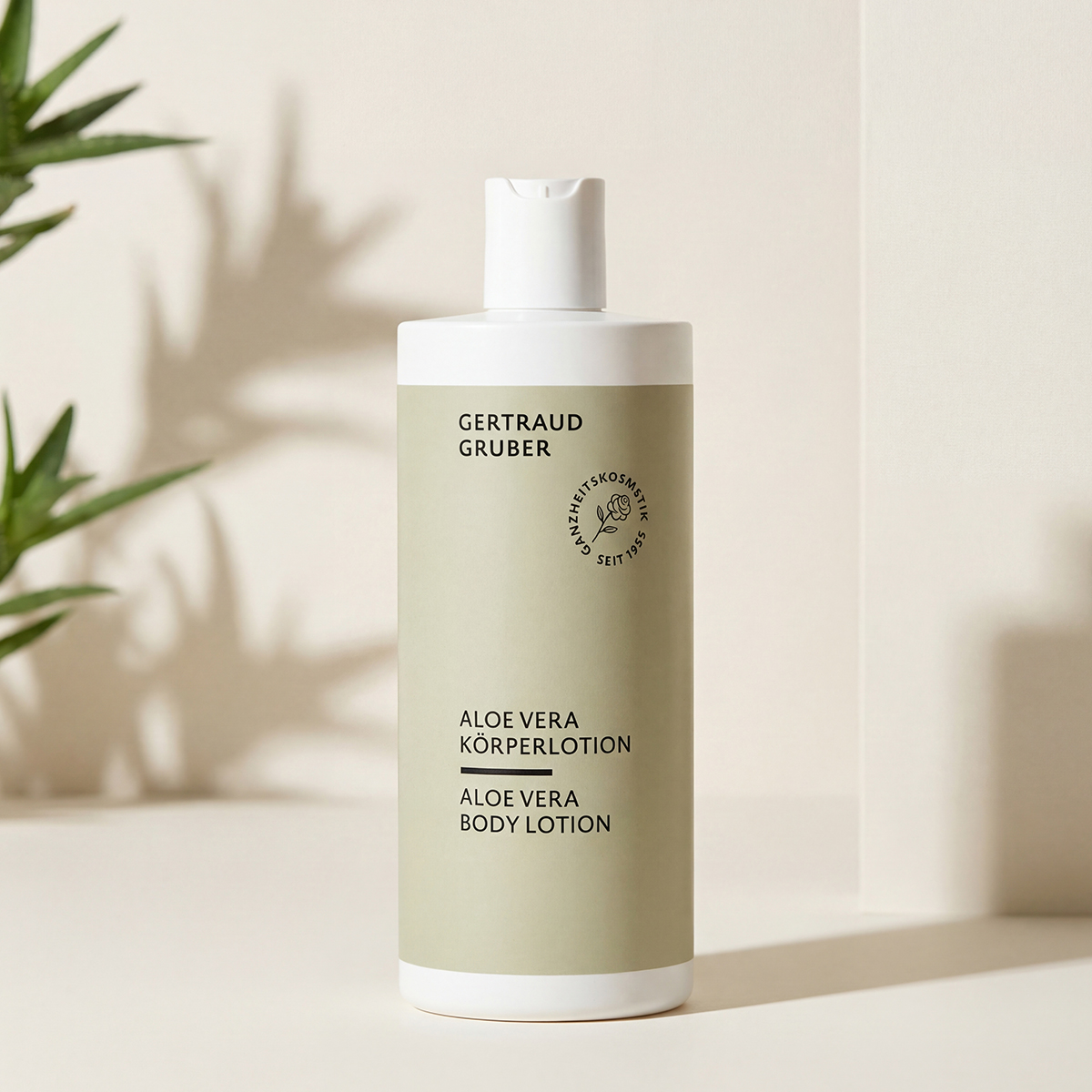 Aloe Vera Bodylotion in grüner Tube vor heller warmen Wand