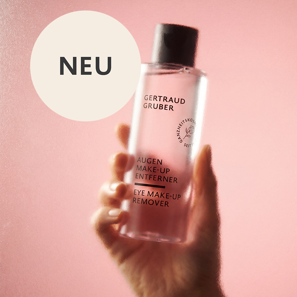 Eine Hand hält den neuen Augen Make-up Entferner von Gertraud Gruber Kosmetik vor rosafarbenem Hintergrund