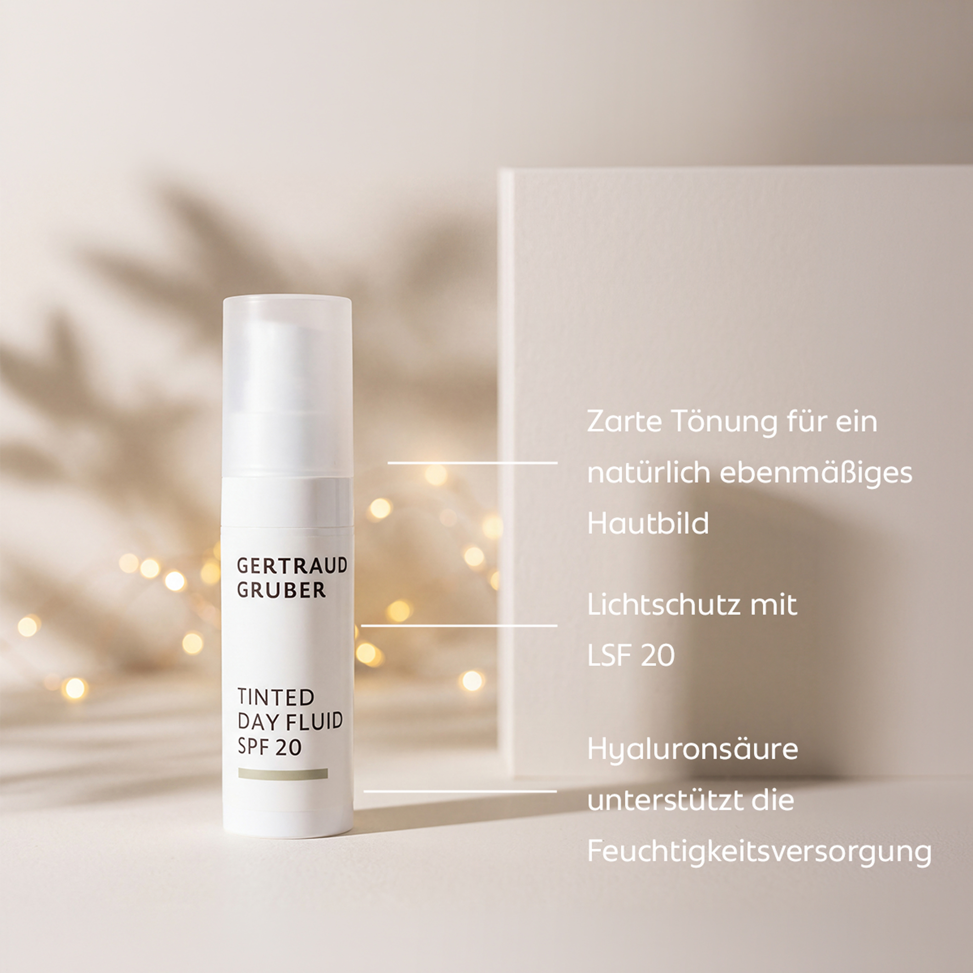 Gertraud Gruber Tinted Day Fluid SPF 20 vor einem hellen, warmen Hintergrund mit dezenten Lichterketten. Rechts stehen die Produktvorteile: zarte Tönung für ein natürlich ebenmäßiges Hautbild, Lichtschutz mit LSF 20