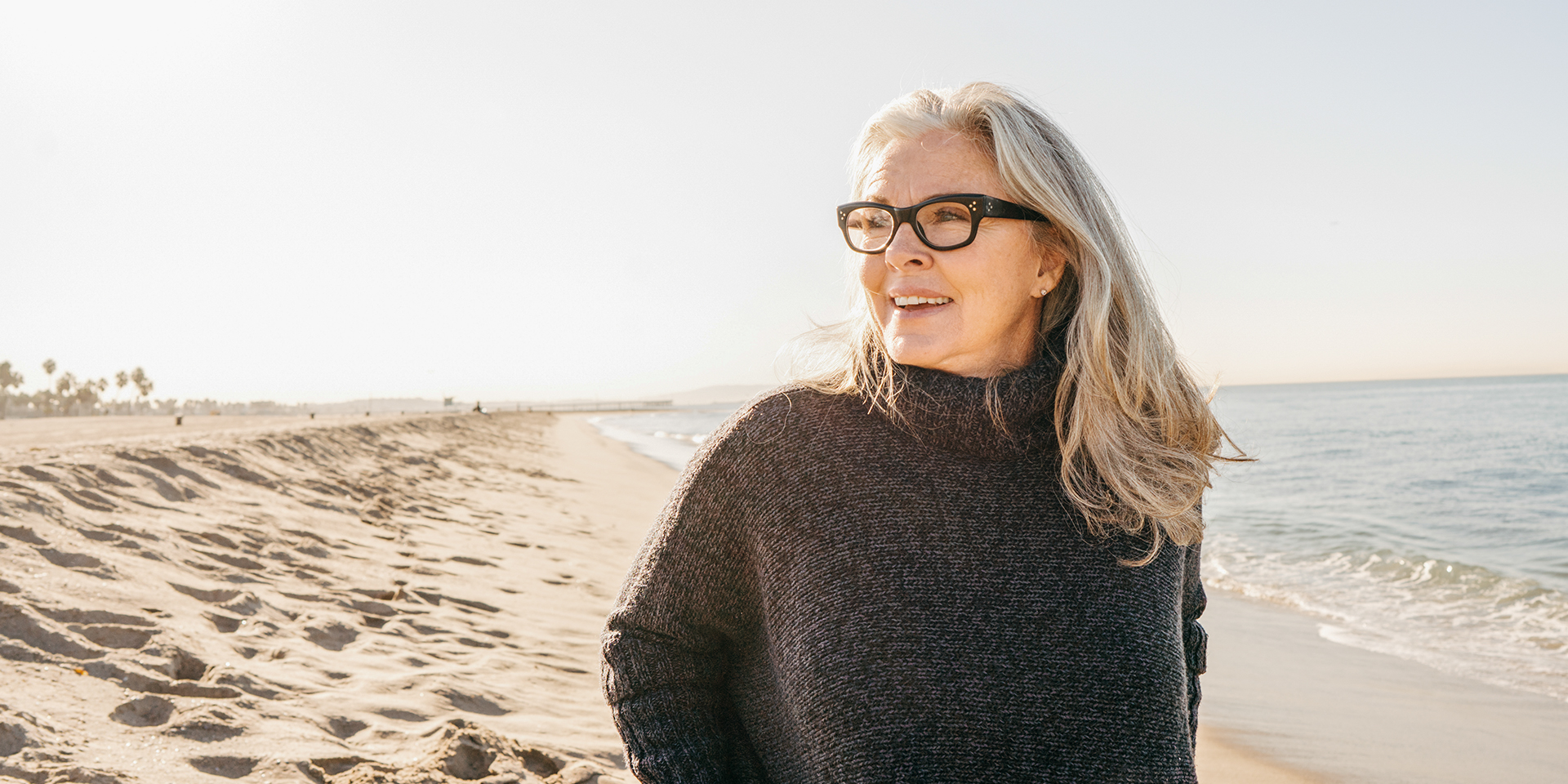 Eine Frau mit Brille steht am Strand und genießt die Sonne.