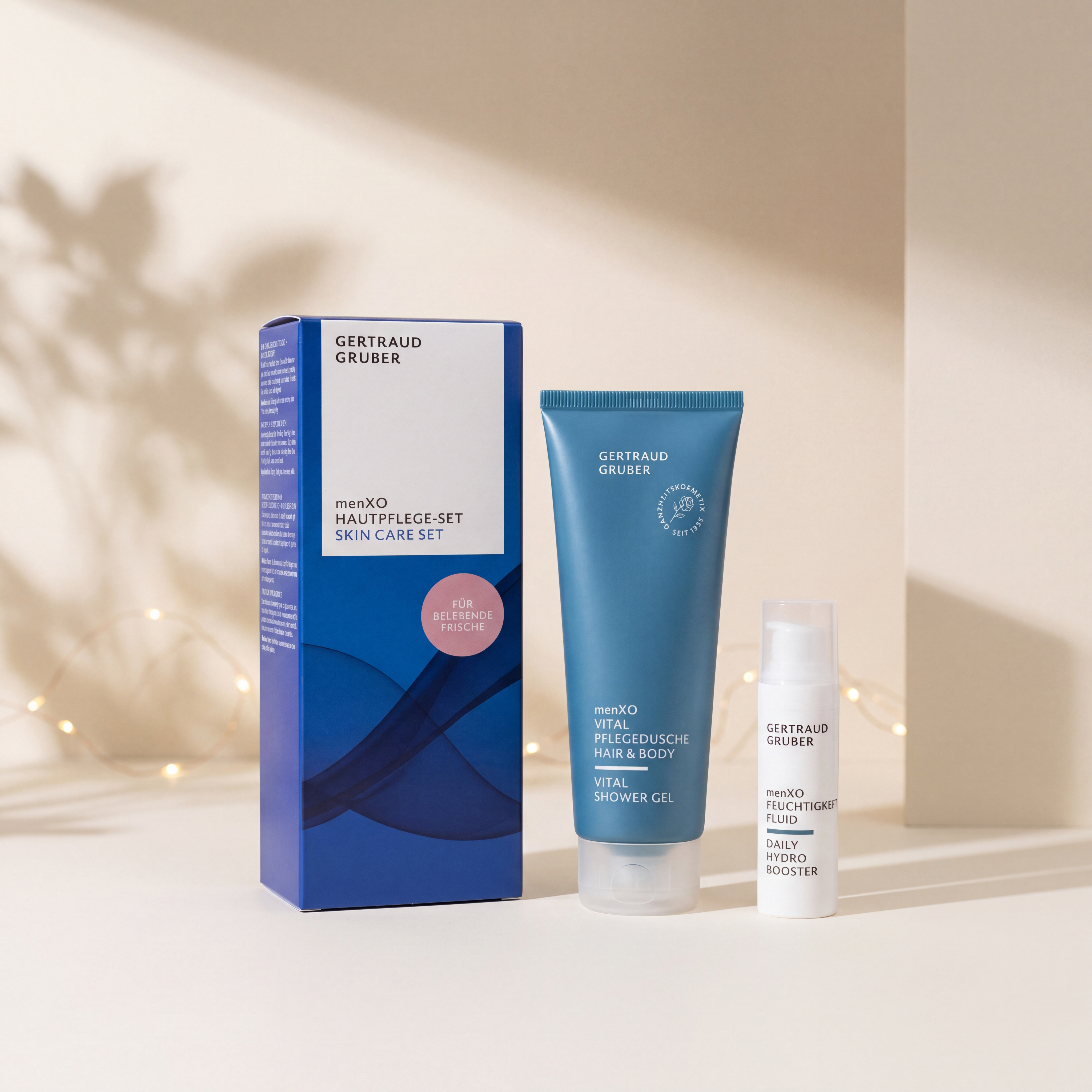 menXO Hautpflege-Set von GERTRAUD GRUBER mit Vital Pflegedusche Hair & Body und Feuchtigkeitsfluid vor der Geschenkverpackung, stimmungsvoll inszeniert mit warmen Lichtern.