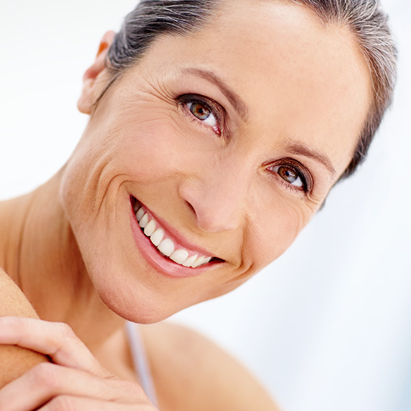 Eine lächelnde Frau mit verschränkten Armen blickt freundlich in die Kamera.