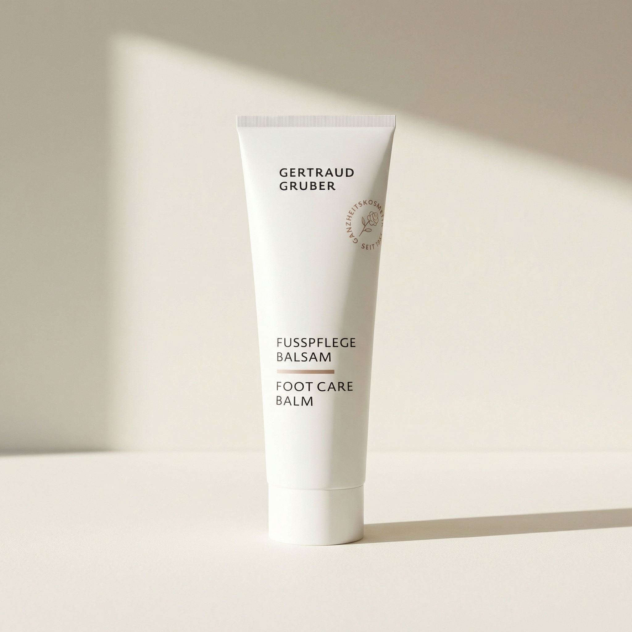 Weiße Tube Ayurasan Fußpflege Balsam von Gertraud Gruber Kosmetik vor ruhigem, hellem Hintergrund