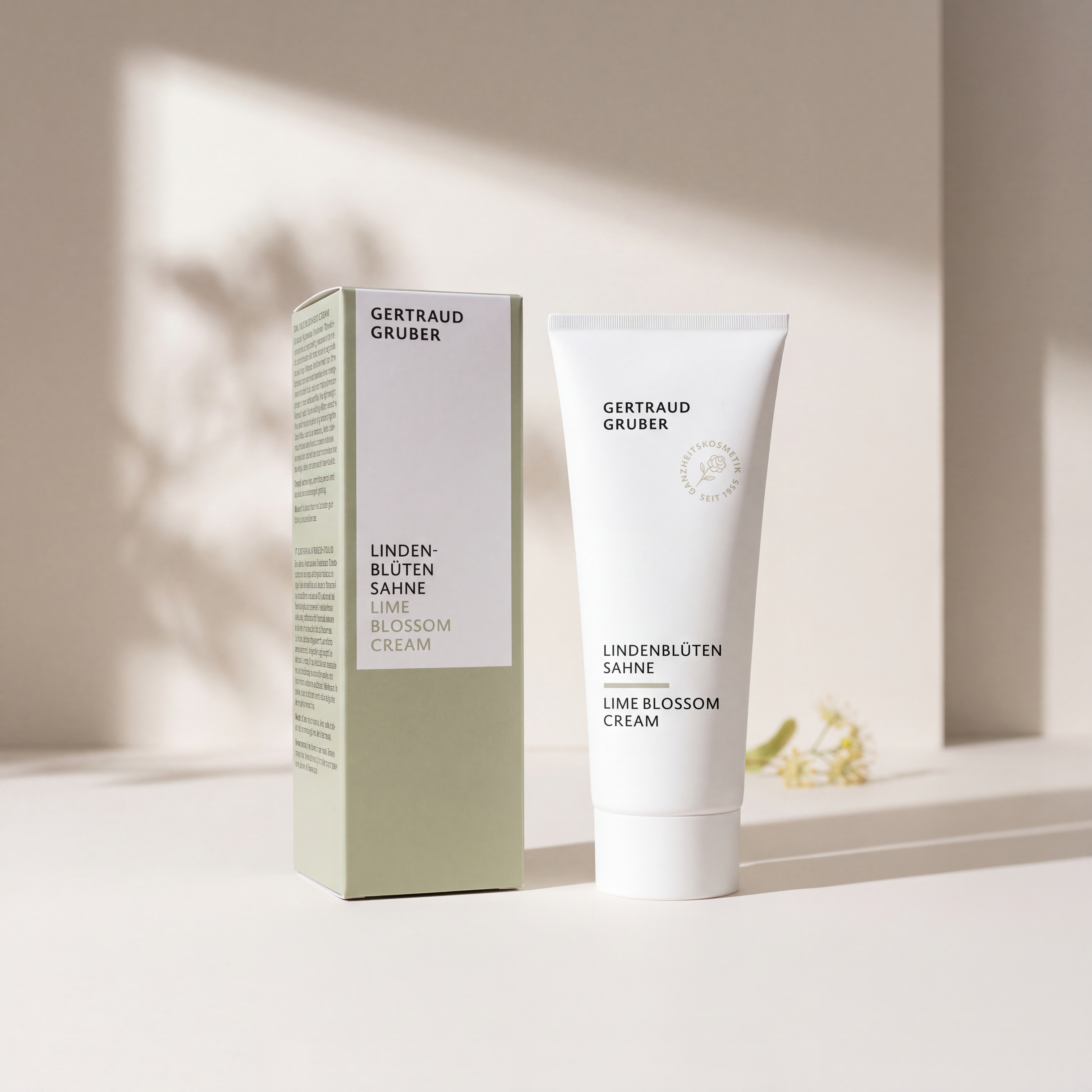 Weiße Tube Lindenblüten Sahne mit grüner Faltschachtel von Gertraud Gruber Kosmetik vor heller Wand mit natürlichem Licht