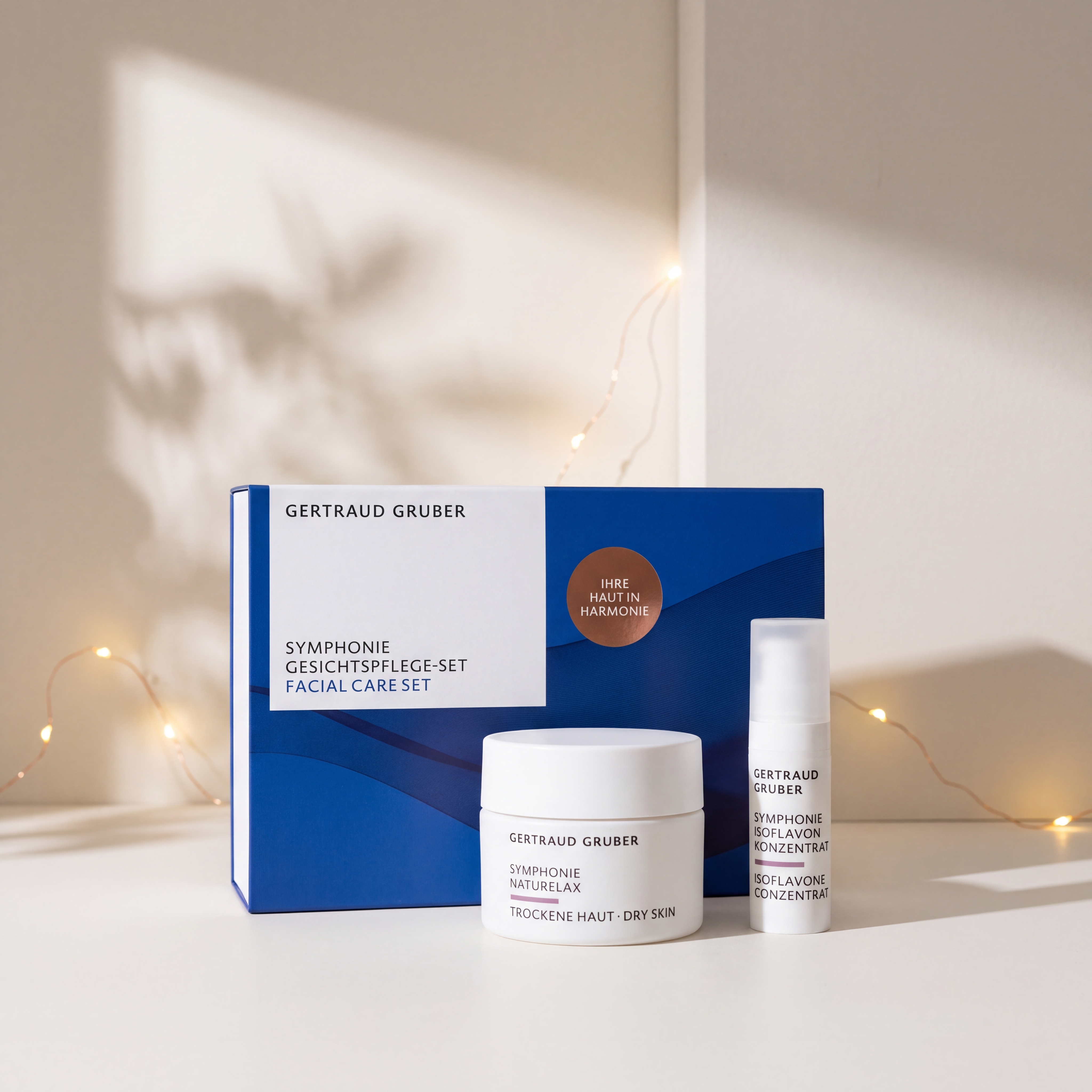 Symphonie Gesichtspflege-Set von GERTRAUD GRUBER mit Naturelax und Isoflavon Konzentrat vor der Geschenkverpackung, stimmungsvoll inszeniert mit warmen Lichtern.