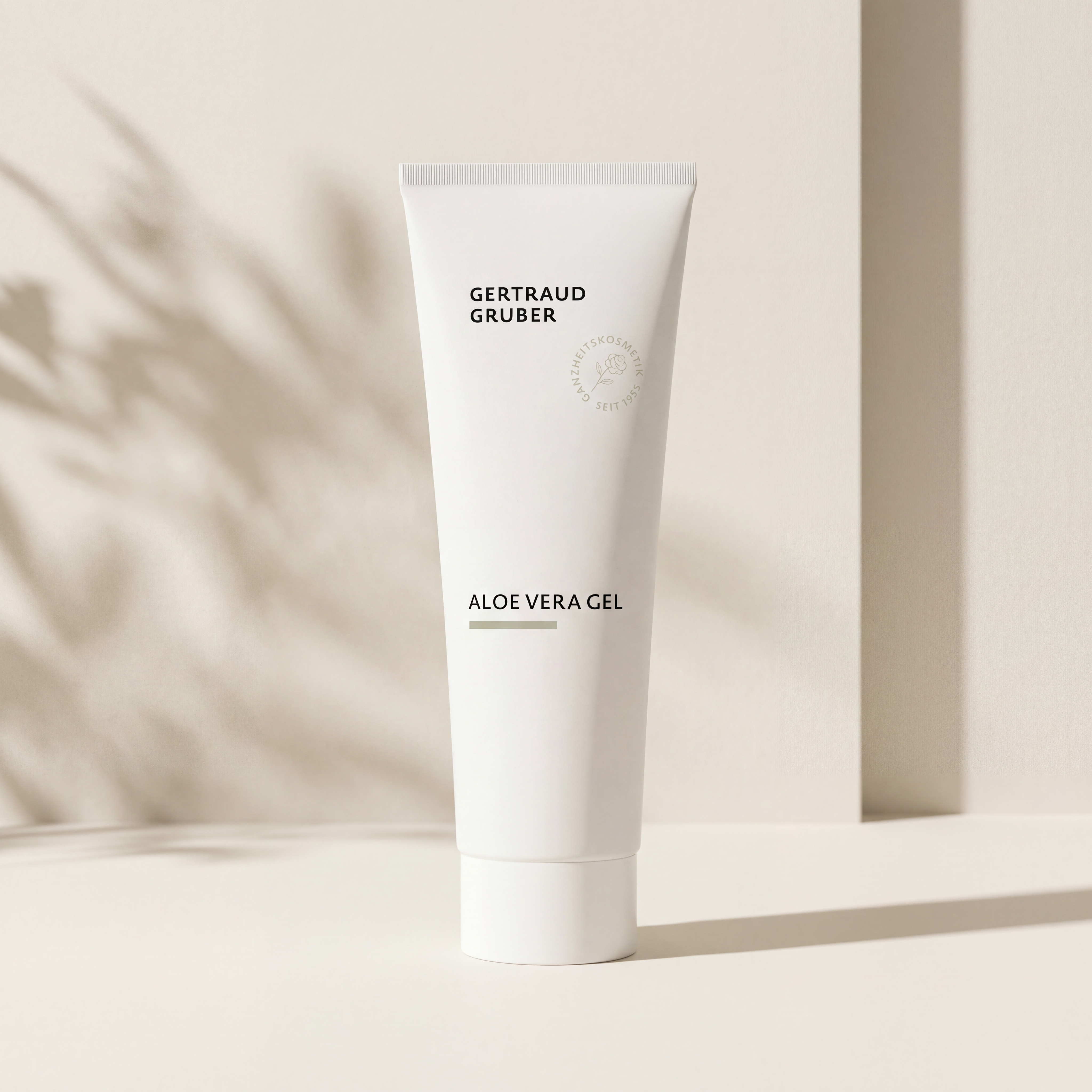 Schlanke weiße Tube Aloe Vera Gel von Gertraud Gruber Kosmetik vor heller Wand mit weichem Schattenspiel