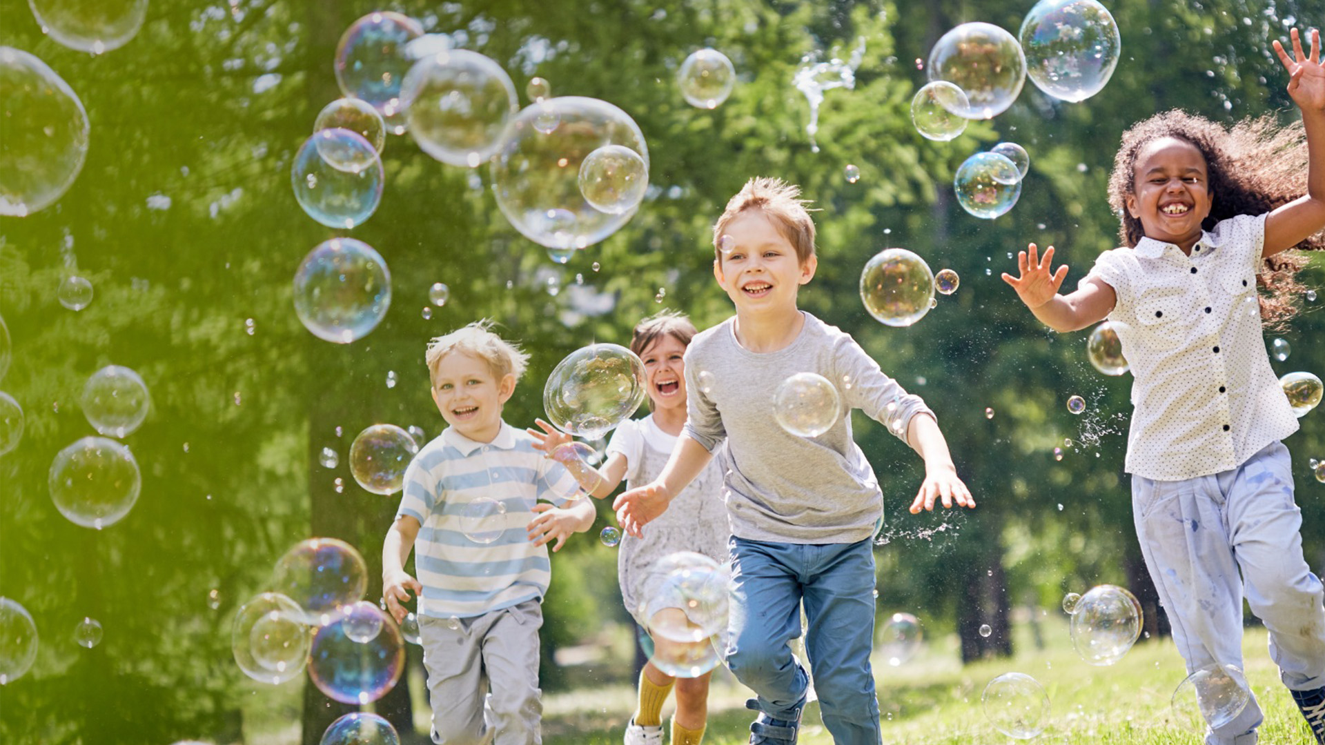 Kinder laufen in Seifenblasen