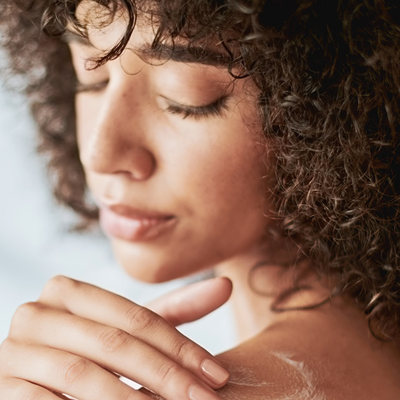 Frau cremt ihre Haut ein