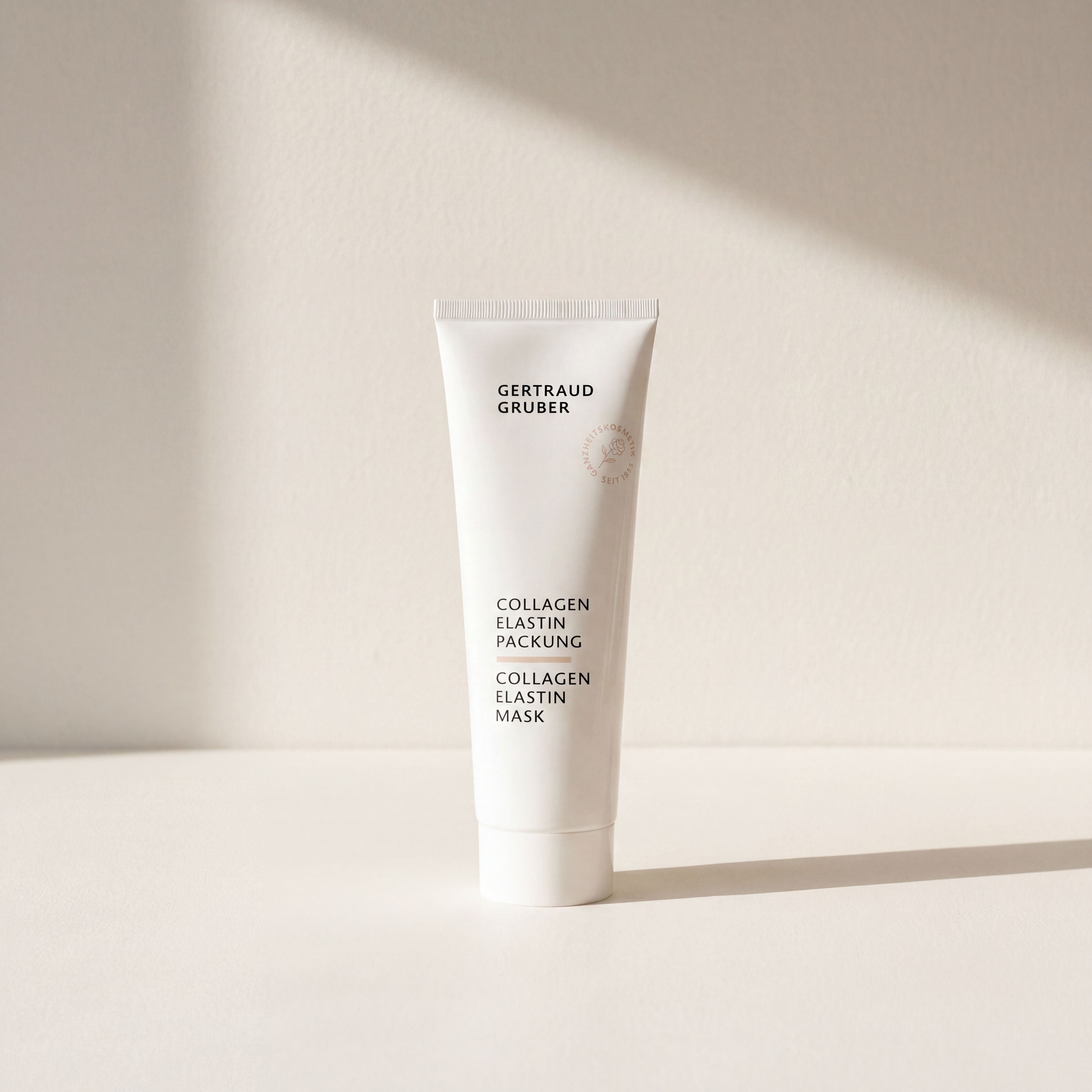 Schlanke weiße Tube Collagen Elastin Packung von Gertraud Gruber Kosmetik vor heller Wand mit sanften Schatten