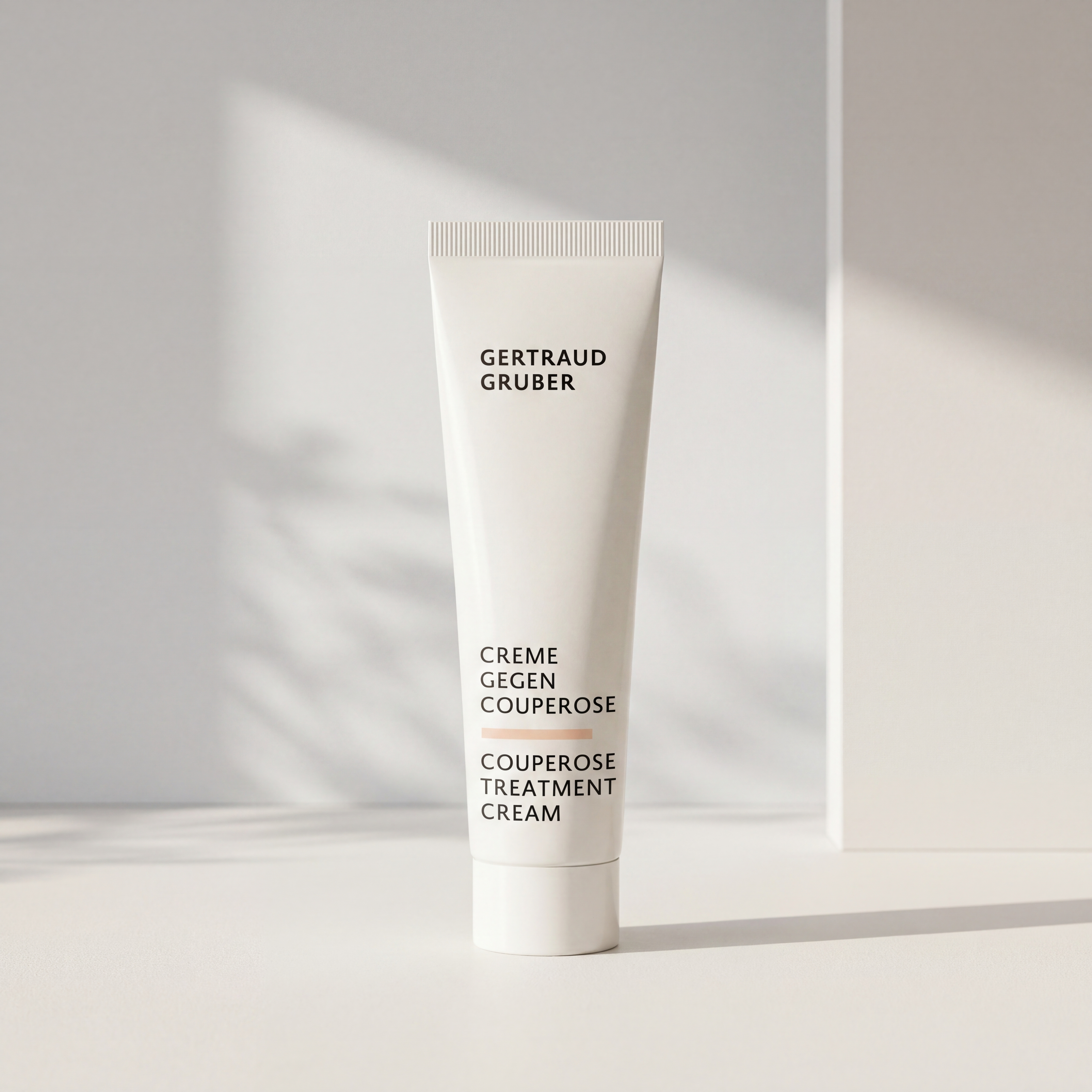 Weiße Tube Creme gegen Couperose von Gertraud Gruber Kosmetik vor heller Wand mit weichem Licht