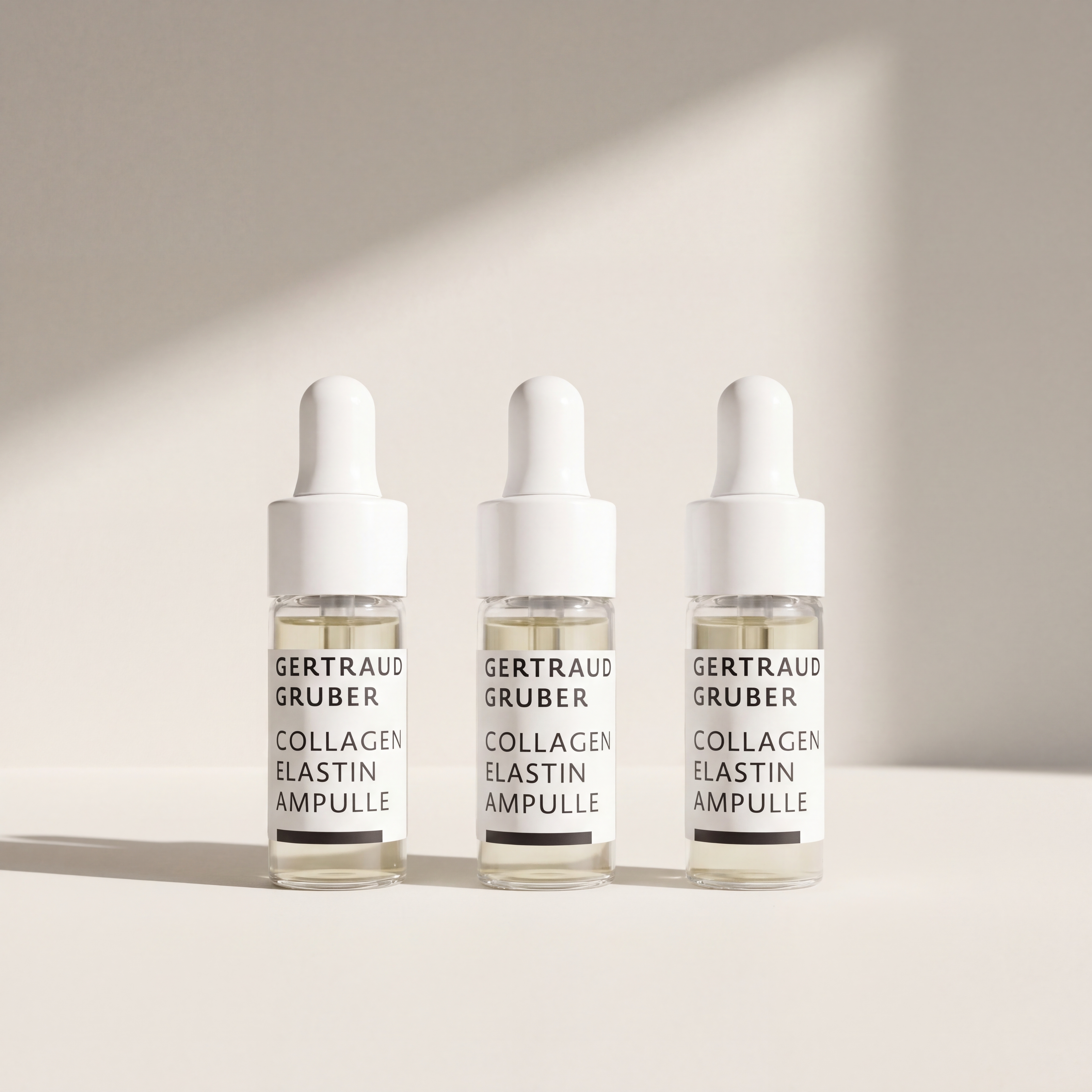 Drei Collagen Elastin Ampullen von Gertraud Gruber Kosmetik in Glasfläschchen mit Pipette vor heller Wand