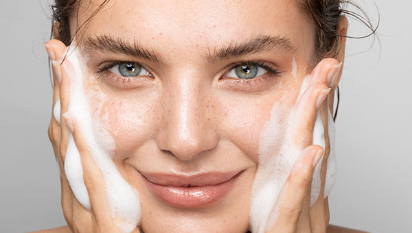 Frau reinigt ihr Gesicht mit Schaum